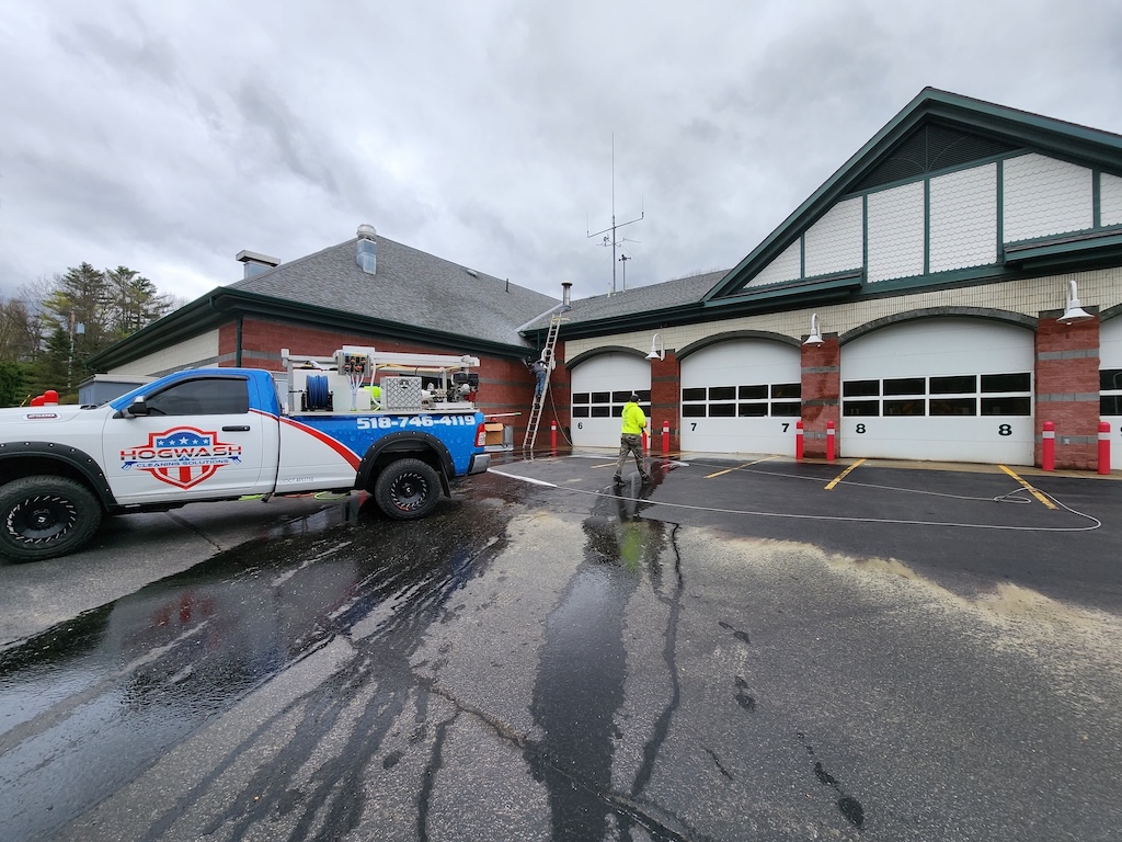 Hogwash pressure washing truck and worker cleaning at fire station